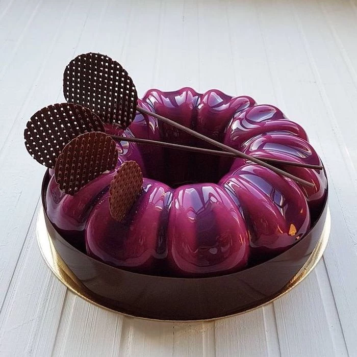 one tier donut cake, covered with pink and purple glaze, placed on gold cake tray, on white wooden surface, galaxy mirror cake