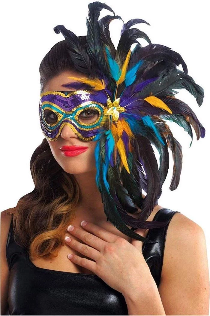 brunette woman wearing black leather top, mask with purple gold green sequins, what to wear to mardi gras, black feathers