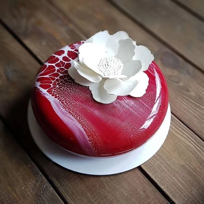 one tier mini cake, covered with red and white marble glaze, white flower decoration on top, glaze icing for cake