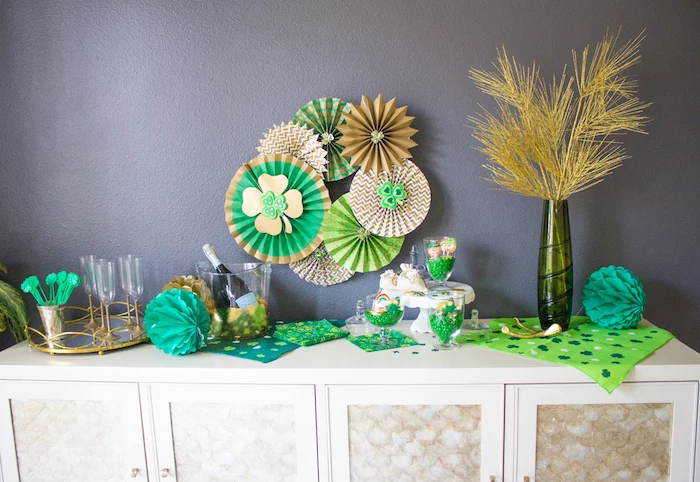 table decorated with green and gold napkins, st patricks day games, champagne and glasses, green candy in glass jars