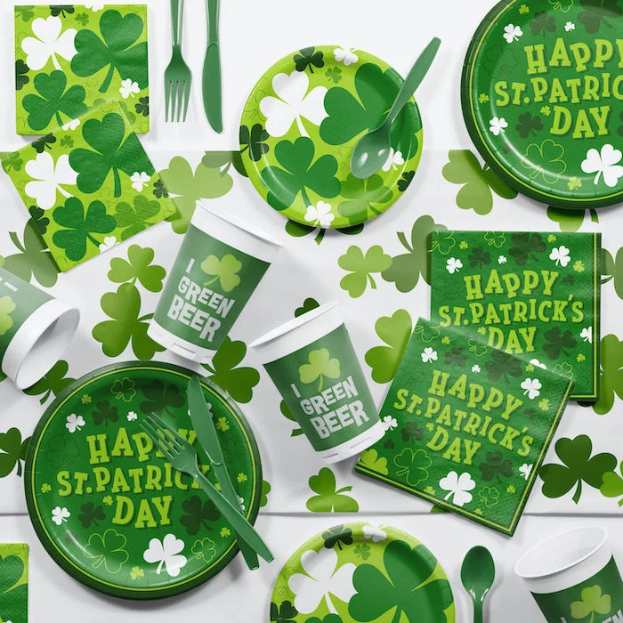 st patrick's day decorations, paper napkins plates cups and utensils, decorated with shamrocks, placed on white table