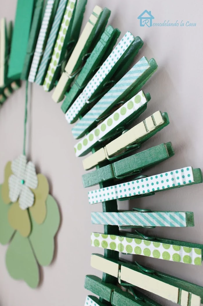happy st patrick's day, wreath made with clothespins, covered with washi tape with different patterns, hanging on white wall
