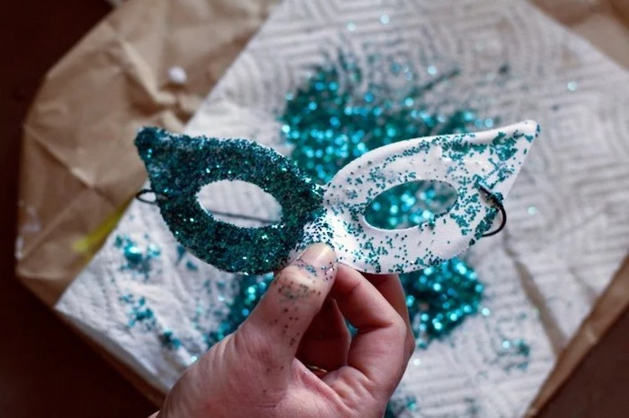 step by step diy tutorial, masquerade masks for couples, white mask covered with turquoise glitter