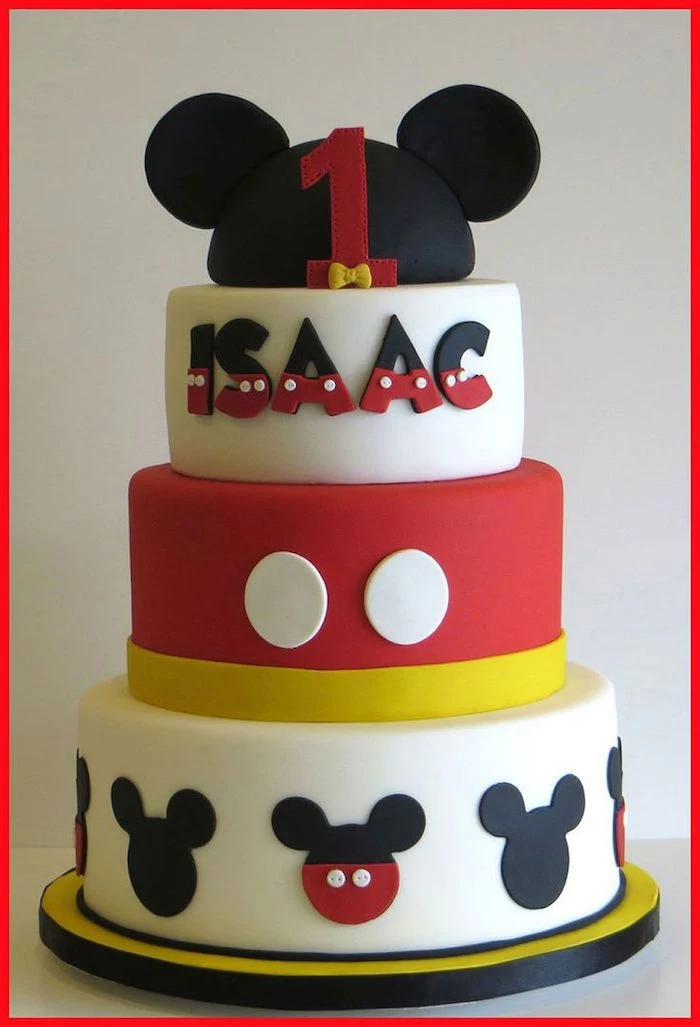 three tier cake, covered with black and white, red and yellow fondant, mickey mouse cake pops, placed on yellow cake tray