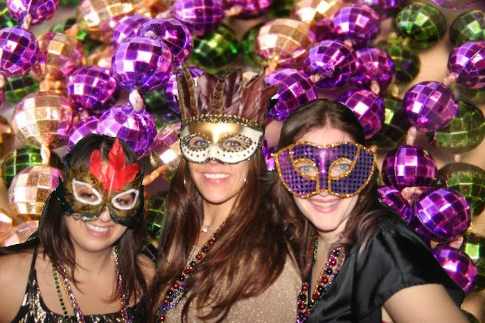 three women smiling, posing for a photograph, what to wear to mardi gras, wearing different masks in gold and purple