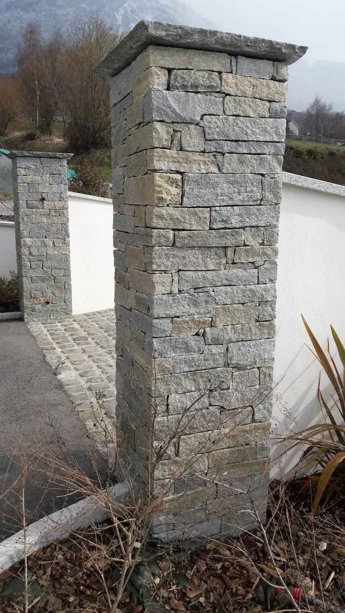 two large poles, made of stone, on both sides of a driveway, natural stone and reclaimed setts, small garden on the side