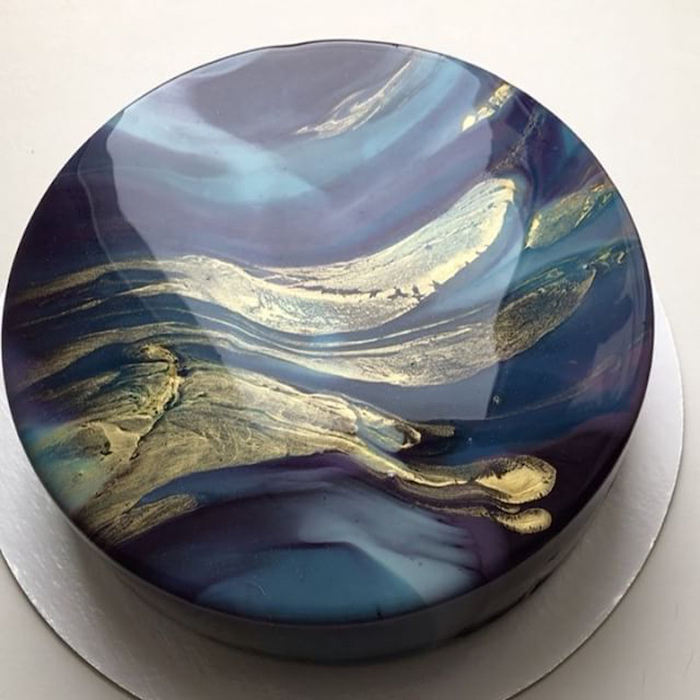 blue and gold marble glaze on one tier cake, placed on silver tray, how to make mirror glaze, white background