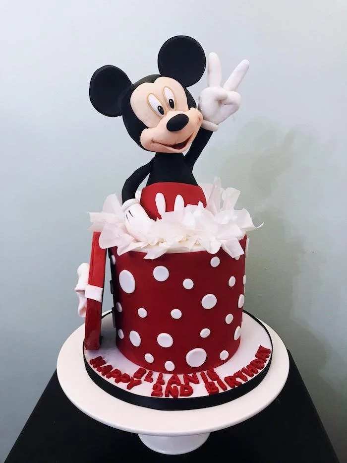 one tier cake, covered with red fondant, placed on white cake stand, mickey cake topper, mickey mouse cake decorations