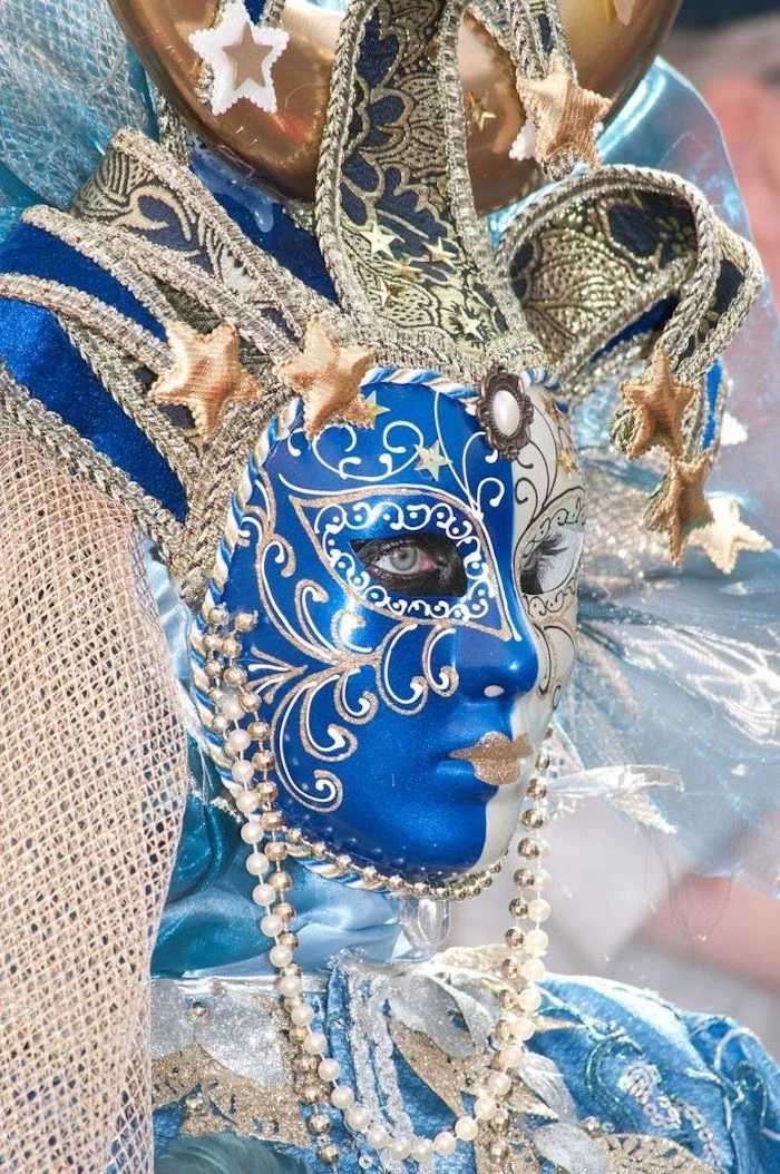 mardi gras mask for men, woman wearing blue satin costume, large jester mask in blue and gold, gold beads around her head