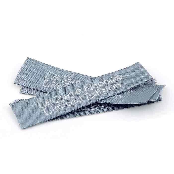 clothing labels, woven grey labels, le zirre napoli limited edition written on them, white background