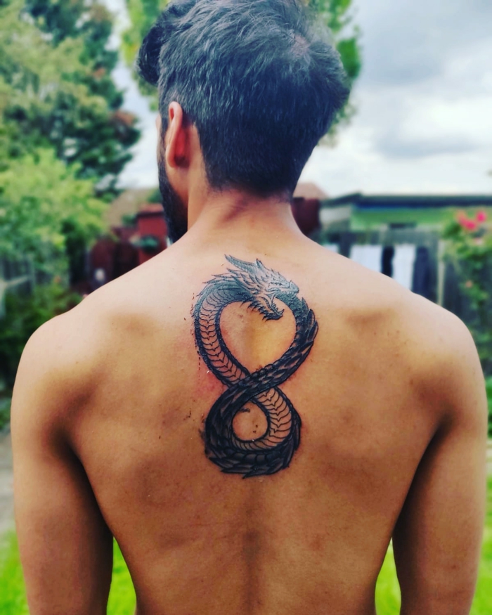 ouroboros tattoo, tattoo on the back of a man with black hair, dragon as an infinity symbol