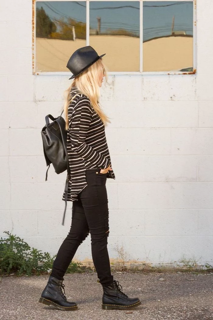 grunge style, blonde woman wearing black jeans, black and white striped blouse, black leather boots hat and backpack, cute outfits for school