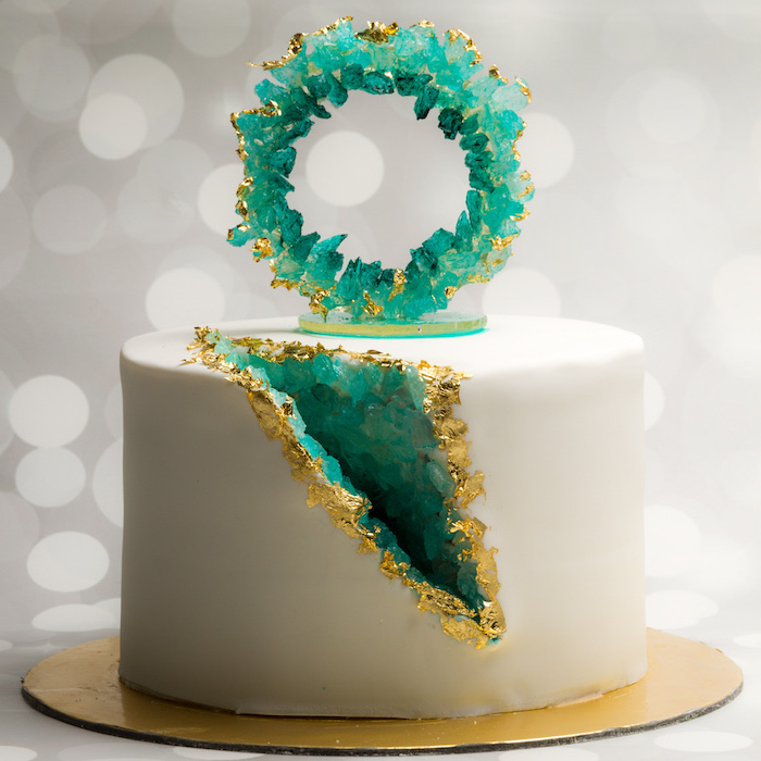 geode cake, one tier cake, covered with white fondant, rock candy painted in turquoise, placed on gold cake tray