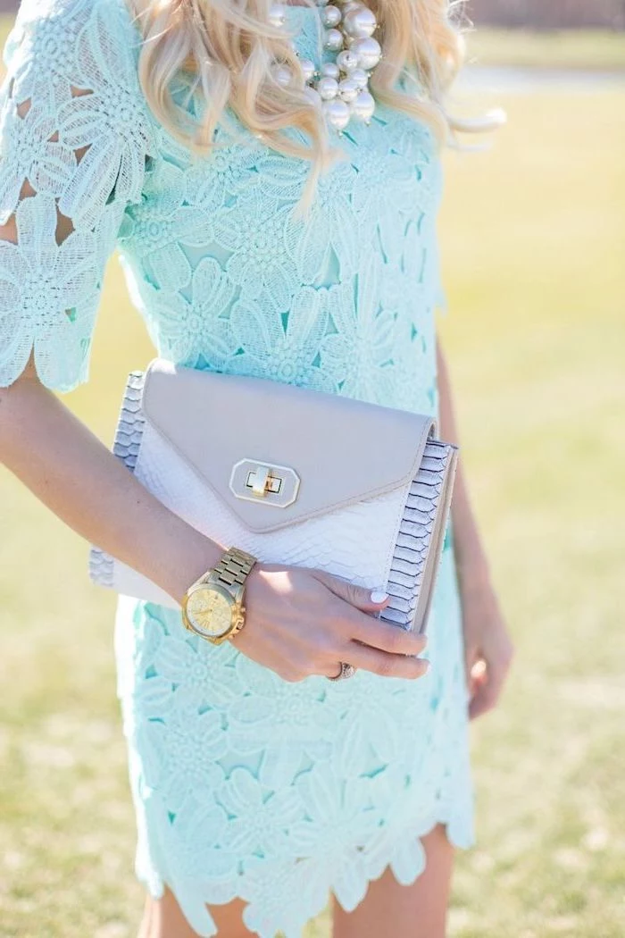 blonde woman wearing blue lace dress, flowy dresses, white pearl necklace and golden watch, leather clutch bag