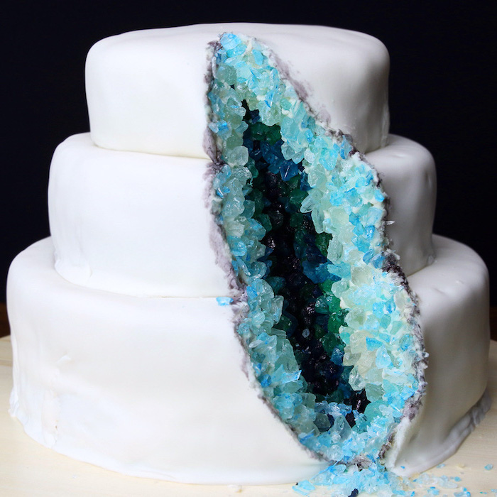 three tier cake, covered with white fondant, decorated with blue and turquoise rock candy, geode wedding cake