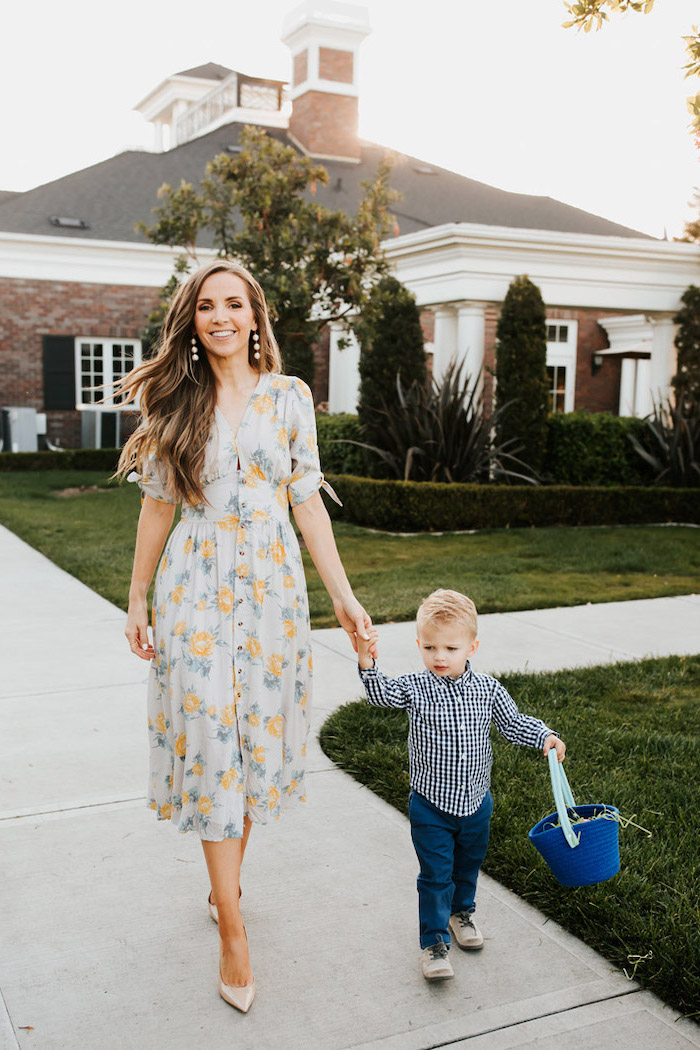 woman with long brown hair, wearing dress with floral print, sunflower dress, holding a little boy by the hand