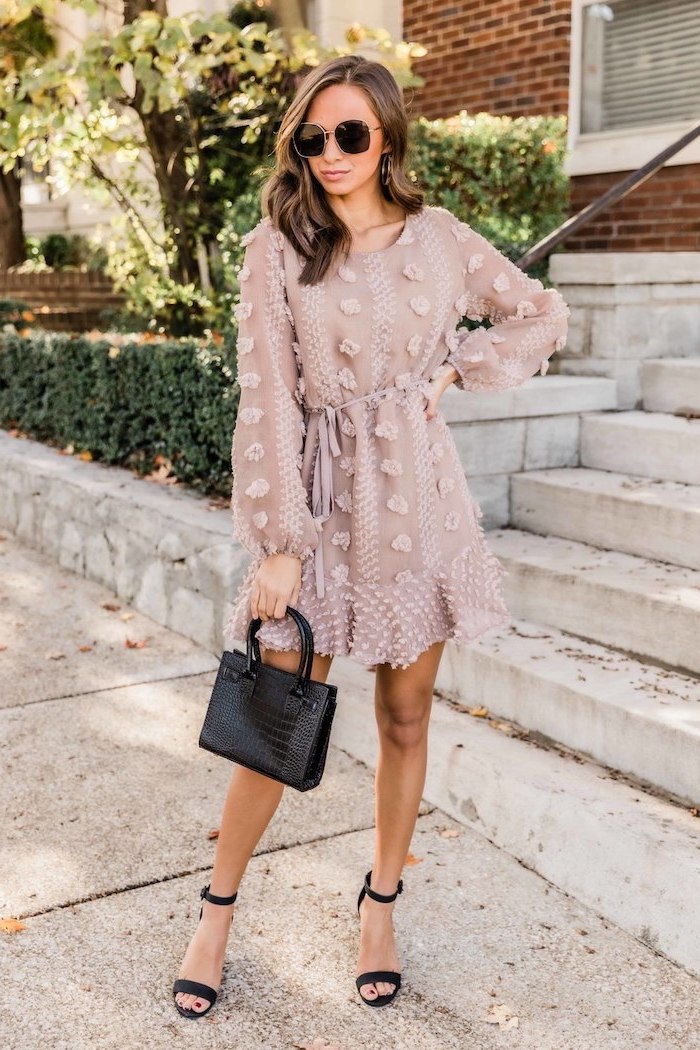 brunette woman wearing sunglasses, sunflower dress, beige dress with long sleeves, black heels and leather bag