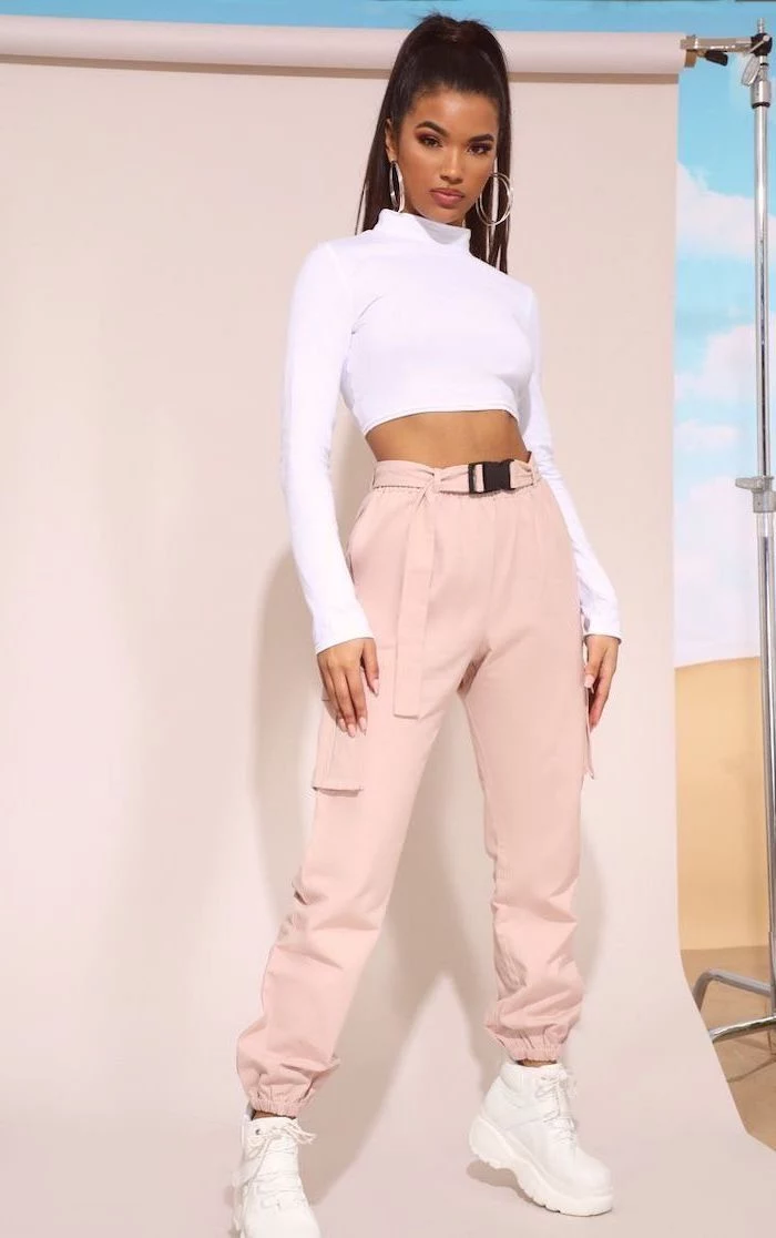 woman with black hair in ponytail, wearing white crop top and blush pink trousers, back to school outfits, white sneakers