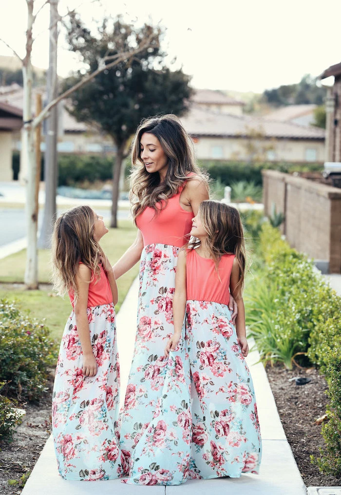 woman standing on a side walk with two girls, wearing identical dresses with floral prints, easter outfits
