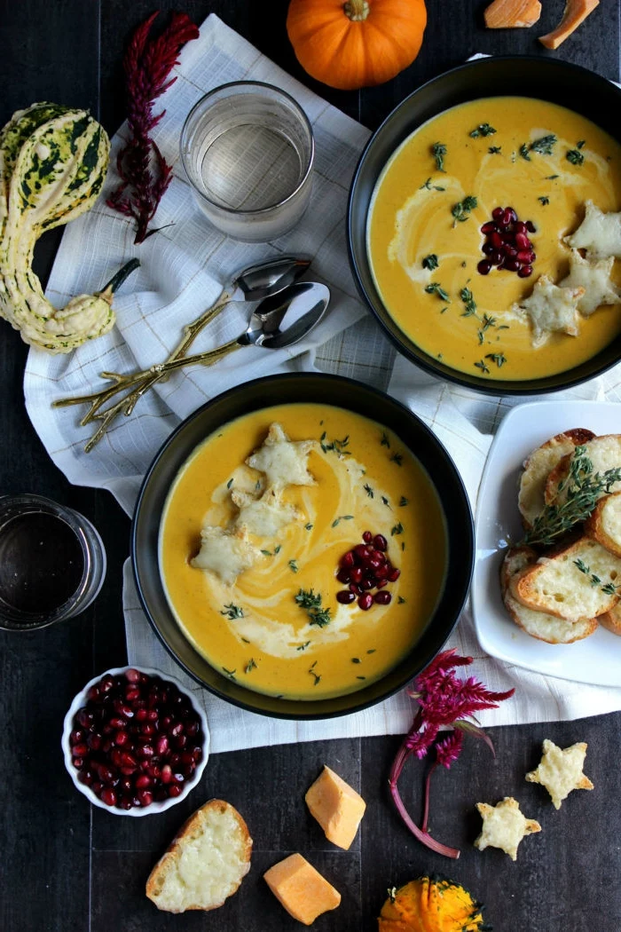 dinner ideas for tonight, butternut squash soup, poured in two black bowls, garnished with pomegranate seeds