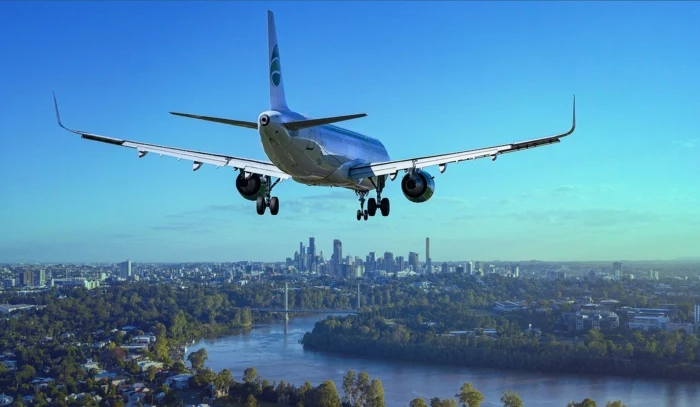 airplane flying low over a river, cheapest flights, city skyline in the background during the day