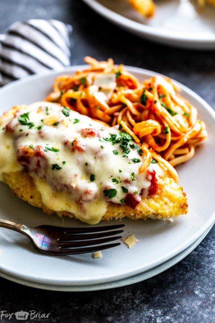 easy dinner recipes for two, chicken parmesan recipe, chicken breast on white plate, fork on the side