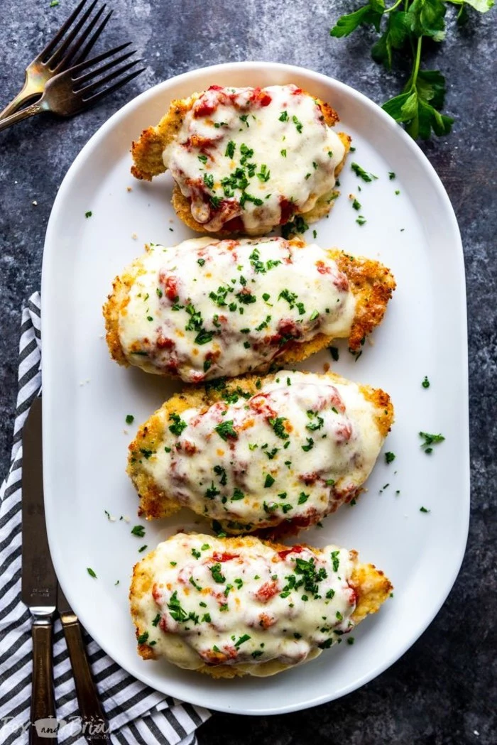 chicken parmesan recipe, easy dinner recipes for two, four chicken breasts, placed on white plate, garnished with parsley
