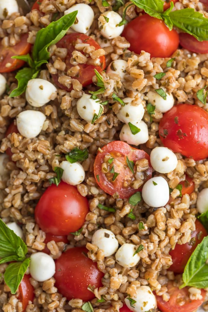 halved cherry tomatoes and baby mozzarella, caprese salad with couscous, traditional easter dinner, basil leaves garnish