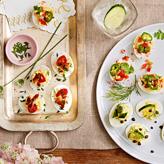 deviled eggs with different garnishes, halved cherry tomatoes and cucumbers, easter lunch ideas, arranged on two plates