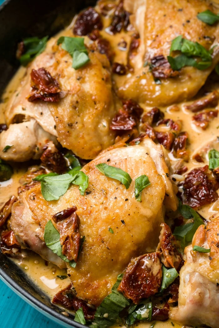 easy dinner recipes for beginners, chicken thighs baked in iron skillet, fresh basil leaves for garnish