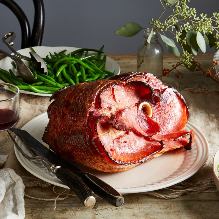 large piece of sliced ham, placed on white plate, easter buffet menu, knife and fork on the side