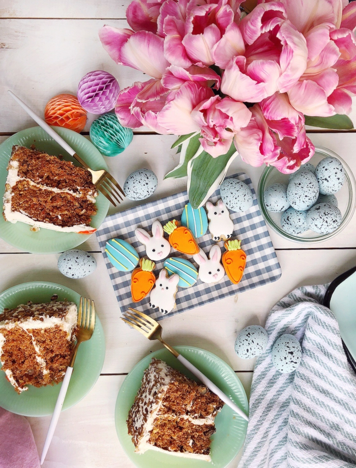 easter dinner ideas, white wooden table, plates with slices of carrot cake on it, bunny shaped cookies