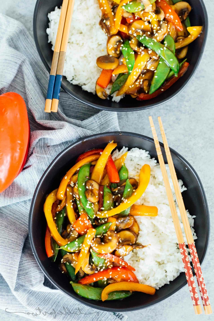 vegetable stir fry with white rice, garnished with sesame seeds, good home cooked meals, poured in two black bowls