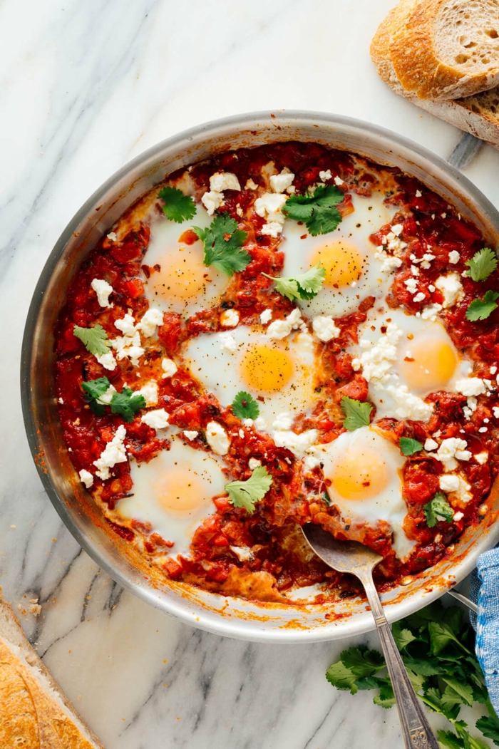 shakshuka with eggs, tomato sauce and crumbled feta cheese, good home cooked meals, garnished with parsley