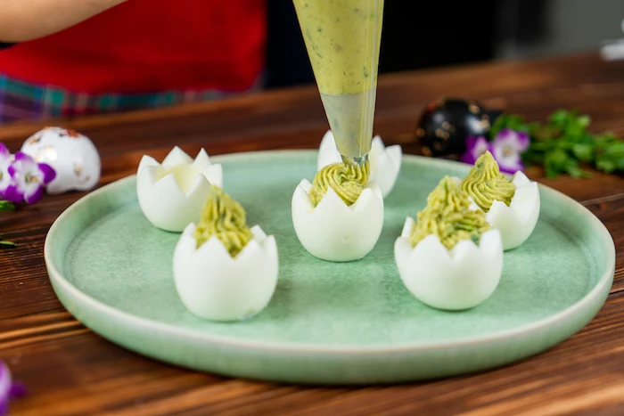 egg whites boiled carved out easter dinner ideas filled with mixture with piping bag placed on green plate
