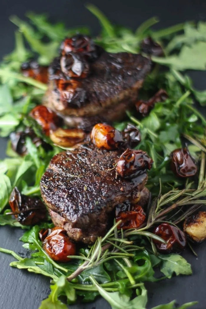 fillet mignon recipe, balsamic tomatoes, dinner ideas for two, green salad underneath, placed on black surface