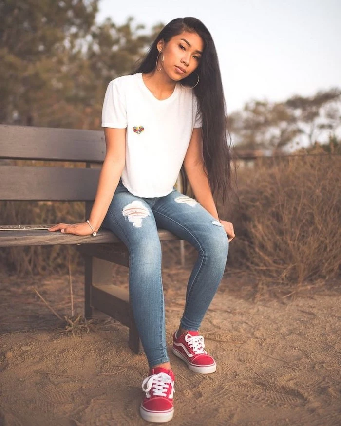 first day of school outfits, girl with long black hair, sitting on a bench, wearing jeans and white t shirt, red vans shoes