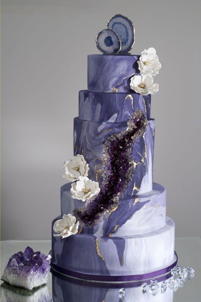 five tier cake, covered with purple and white marble fondant, geode cupcakes, decorated with purple rock candy and flowers