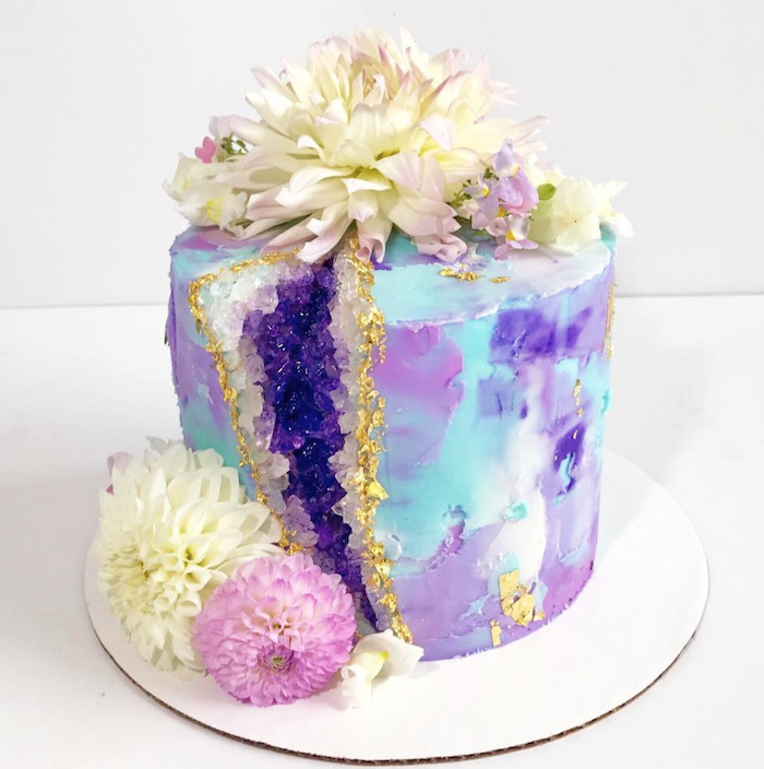 one tier cake with colorful buttercream, geode cupcakes, decorated with white and purple rock candy and flowers