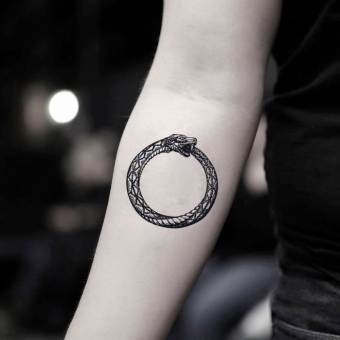 ouroboros symbol, forearm tattoo, woman wearing black shirt, blurred background