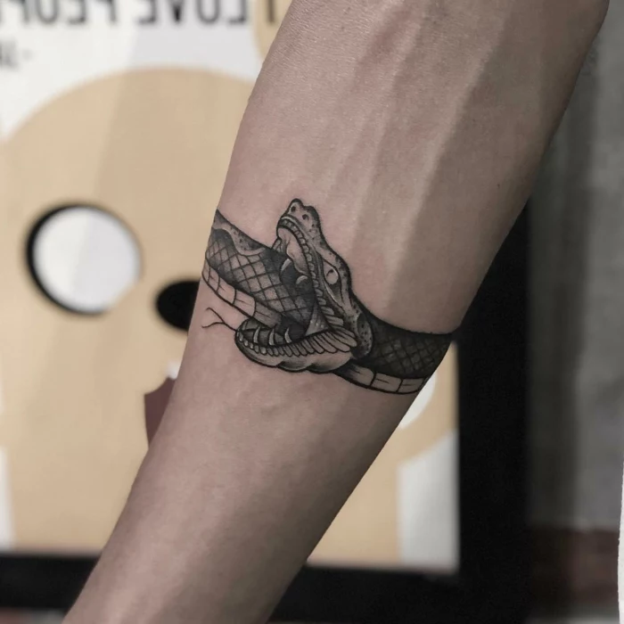 snake wrapped around the arm, forearm tattoo, ouroboros symbol, blurred background