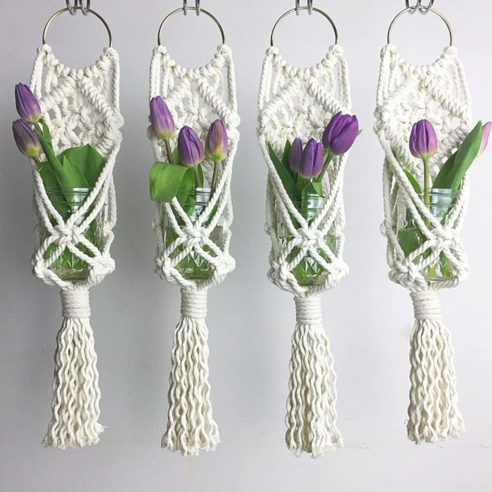 four glass jars with purple tulips inside, hanging from the ceiling, macrame plant hanger tutorials, white background