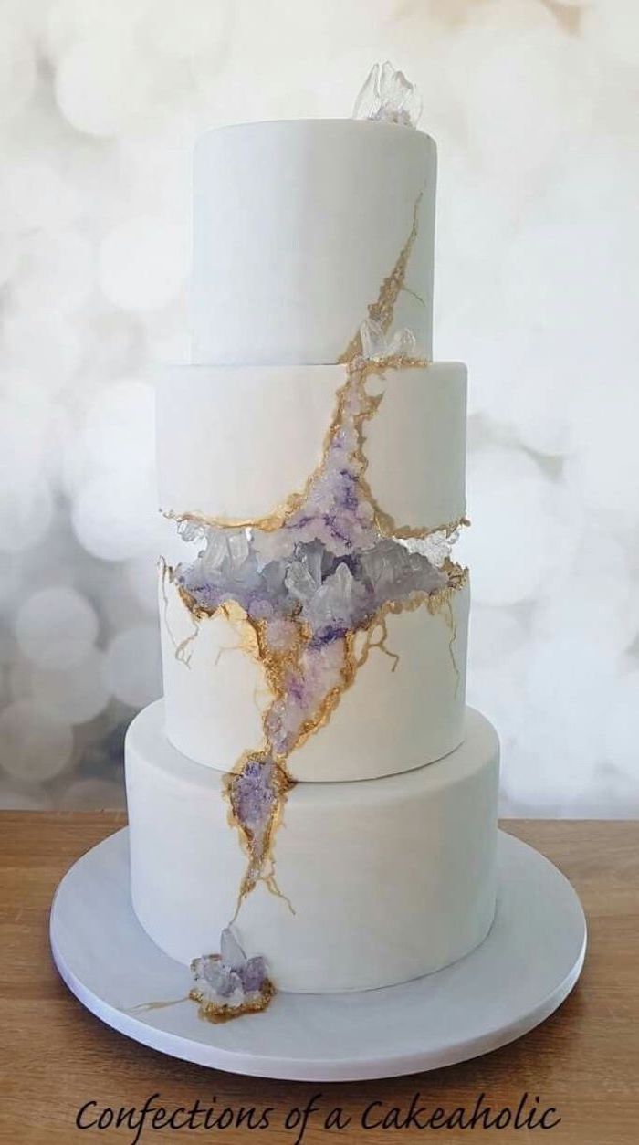 four tier cake, covered with white fondant, decorated with white and purple rock candy, how to make a geode cake