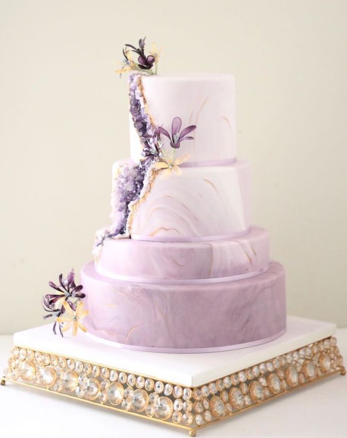 four tier cake, covered with purple and white marble fondant, how to make a geode cake, decorated with purple rock candy and flowers