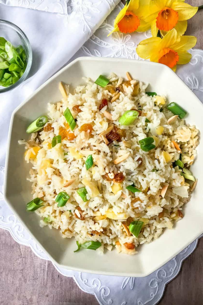 rice pilaf in white hexagonal plate, placed on white table runner, traditional easter dinner, flowers on the side