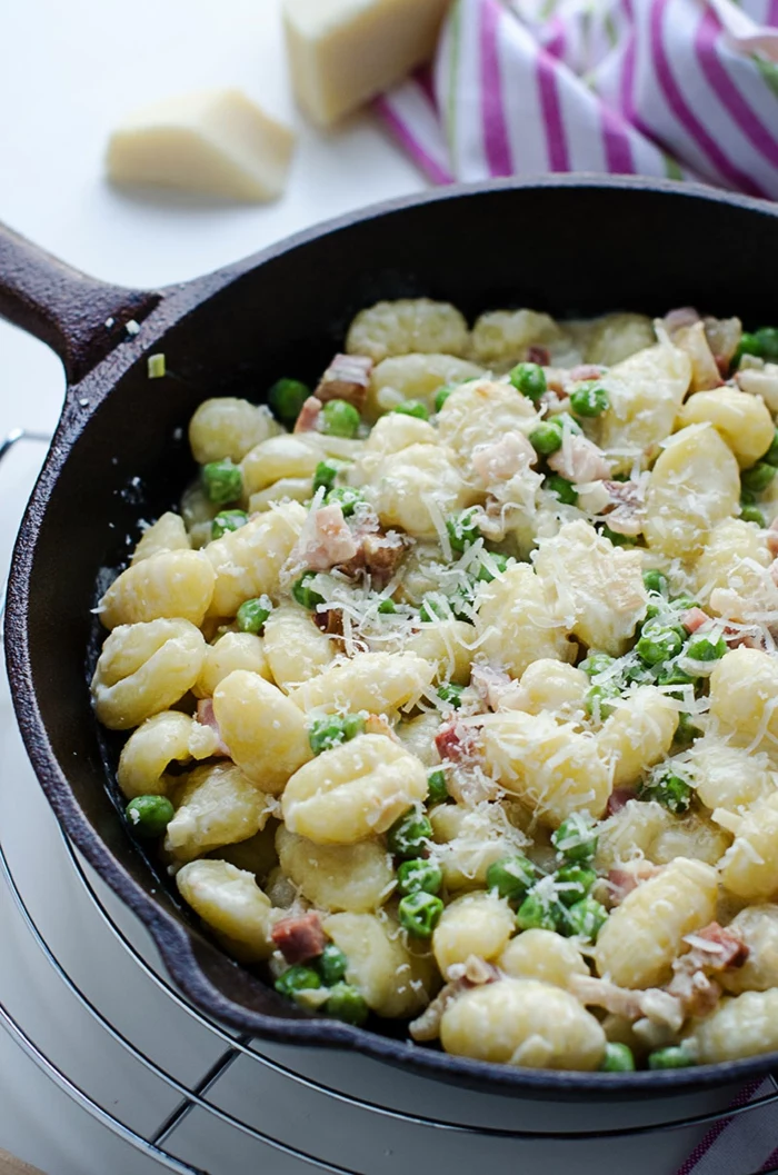 gnocchi with peas and bacon, grated parmesan cheese on top, quick and easy dinner recipes, cooked in an iron skillet