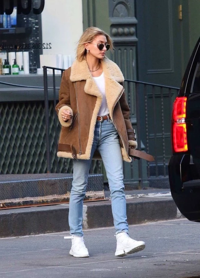 hailey bieber walking on the road, wearing jeans and white t shirt, brown jacket and white sneakers, first day of school outfits