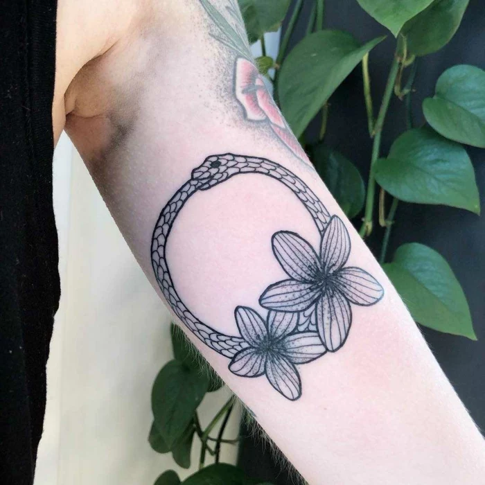 inside of the arm tattoo, ouroboros symbol, snake with two flowers underneath, mand wearing black top