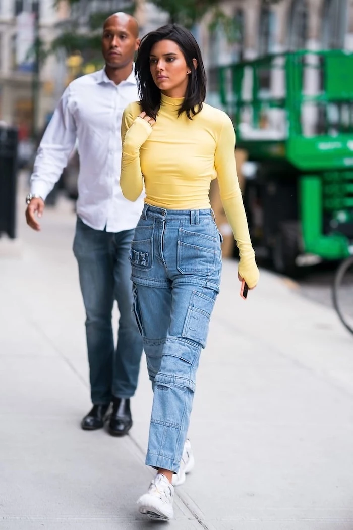 kendall jenner walking on a sidewalk, cute outfits with leggings, wearing jeans with lots of pockets, yellow polo blouse
