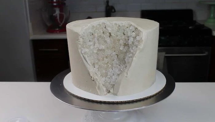 crystal cake, one tier cake covered with white fondant, white rock candy placed on the side, placed on silver cake stand